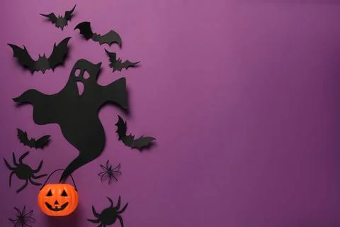 Flat lay composition with paper ghost, bats and plastic pumpkin basket on pur Stock Photos