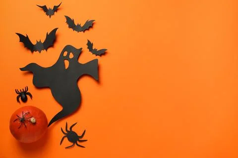 Flat lay composition with paper ghost, bats and pumpkin on orange background, Stock Photos