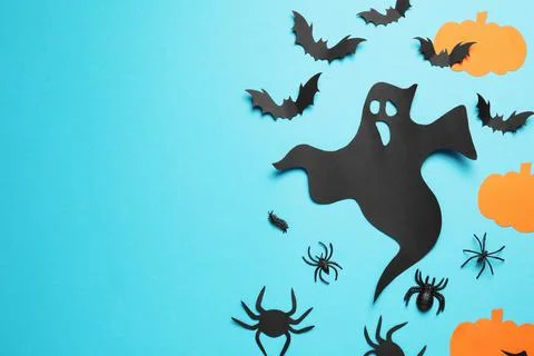Flat lay composition with paper ghost, bats and pumpkins on light blue backgr Stock Photos