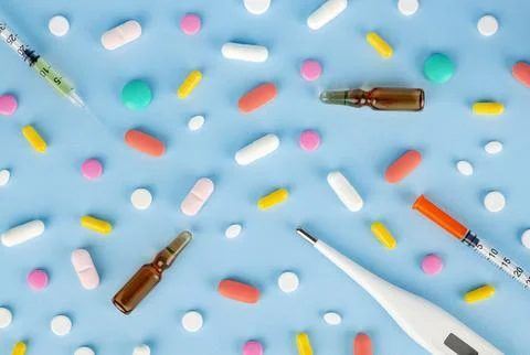 Flat lay composition with pills, thermometer and syringe on blue background. Stock Photos