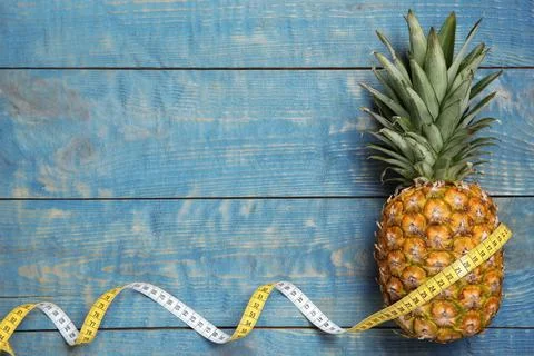 Flat lay composition with pineapple, measuring tape and space for text on woo Stock Photos