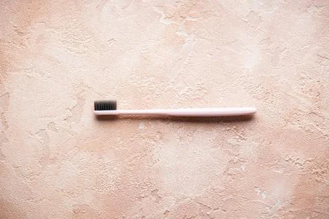 Flat lay composition of pink toothbrush with black bristles on a beige backgr Stock-Fotos