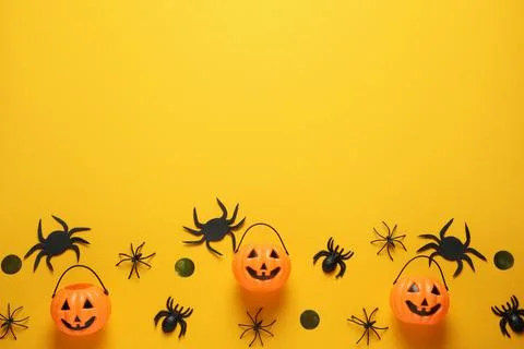 Flat lay composition with plastic pumpkin baskets, spiders and golden confett Stock Photos