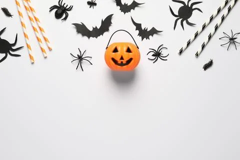 Flat lay composition with plastic pumpkin basket and paper bats on white back Stock Photos