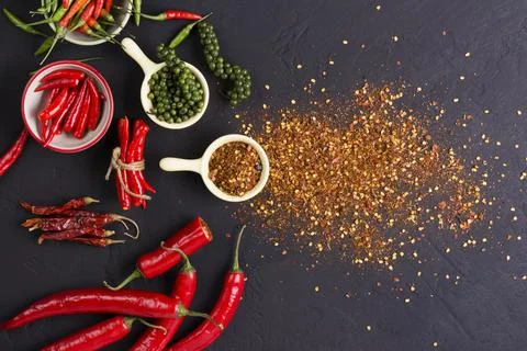 Flat lay composition with powdered and raw chili peppers on dark background.  Foto stock