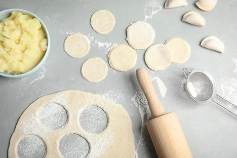 Flat lay composition with raw dumplings and dough on grey background. Process Foto stock
