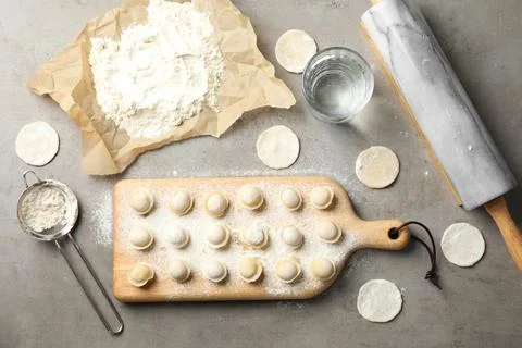 Flat lay composition with raw dumplings on grey background. Process of cookin 写真素材