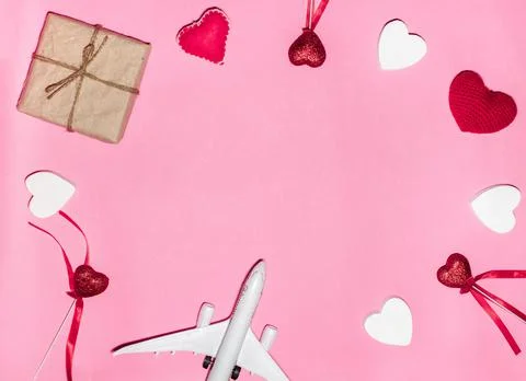 Flat lay composition with of red and white hearts, passenger airplane, and gift Foto stock