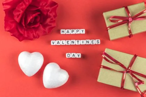 Flat lay composition on red paper background with white hearts, gifts, rose a Stock Photos