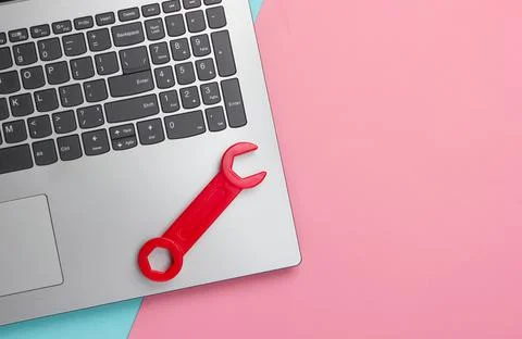 Flat lay composition. Repair concept. Laptop with toy wrench on pink blue pas Stock Photos