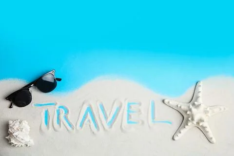 Flat lay composition with sand, sunglasses and word TRAVEL on color backgroun Foto stock