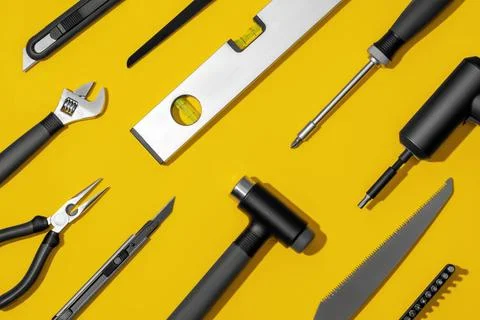 Flat lay composition with set of home repair tools on bright yellow background. Stock Photos