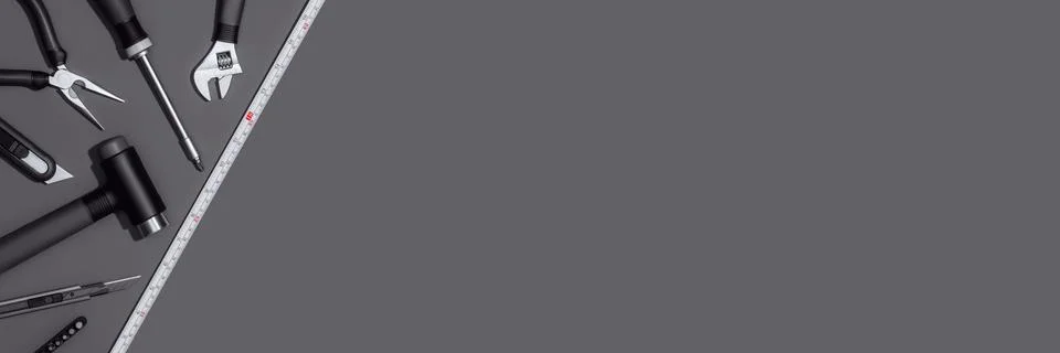 Flat lay composition with set of home repair tools on dark grey background. Stock Photos