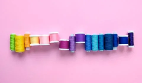 Flat lay composition of sewing threads on color pink background. Space for text. Stock Photos