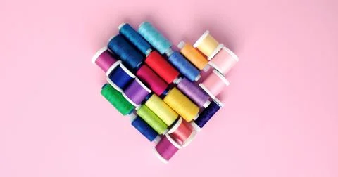 Flat lay composition of sewing threads in the shape of a heart on color pink Stock Photos
