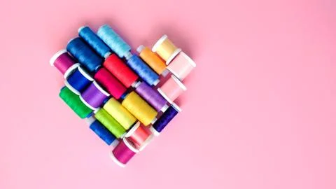 Flat lay composition of sewing threads in the shape of a heart on color pink Stock Photos