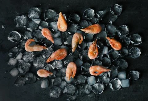 Flat lay composition with shrimps and ice cubes on dark background Stockfoto's