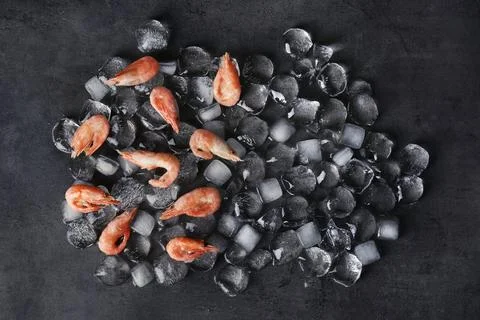 Flat lay composition with shrimps and ice cubes on dark background Stockfoto's