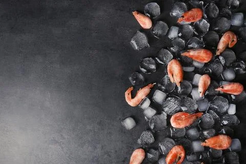 Flat lay composition with shrimps, ice cubes and space for text on dark backg Stockfoto's