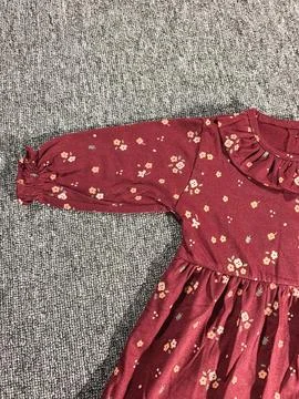 Flat lay composition of a small maroon patterned baby girl dress on grey ba.. Stock Photos