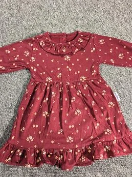 Flat lay composition of a small maroon patterned baby girl dress on grey ba.. Stock Photos