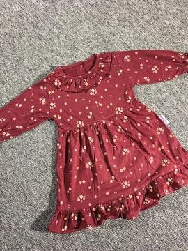 Flat lay composition of a small maroon patterned baby girl dress on grey ba.. Stock Photos
