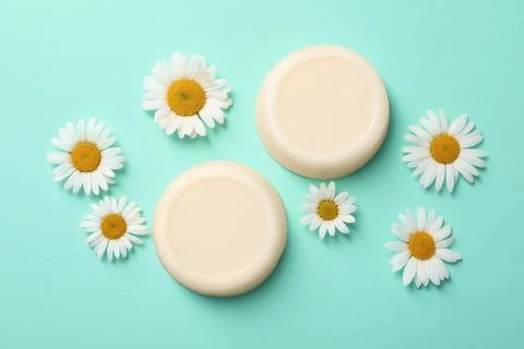 Flat lay composition with solid shampoo bars and chamomiles on turquoise back Foto stock