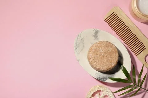 Flat lay composition of solid shampoo bar, leaf and comb on pink background.  Foto stock