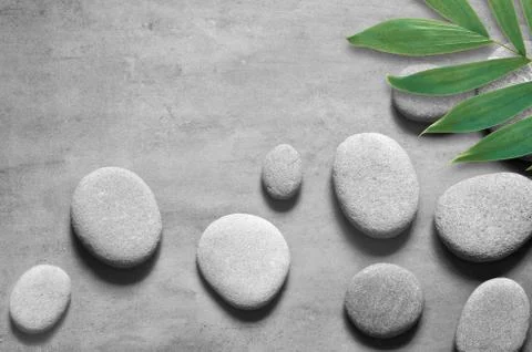Flat lay composition with spa stones, palm leaves on grey background. Stock Photos