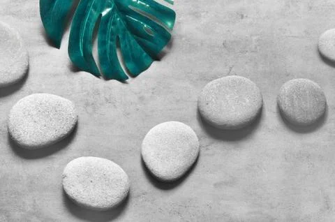 Flat lay composition with spa stones, palm leaves on grey background. Stock Photos