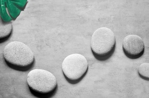 Flat lay composition with spa stones, palm leaves on grey background. Stock Photos