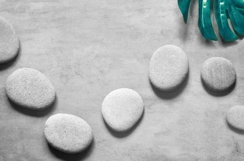 Flat lay composition with spa stones, palm leaves on grey background. Stock Photos