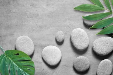 Flat lay composition with spa stones, palm leaves on grey background. Stock Photos