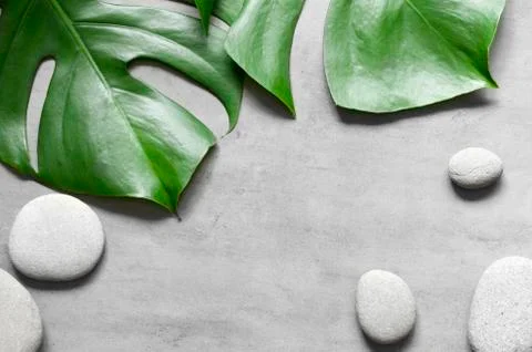 Flat lay composition with spa stones, palm leaves on grey background. Stock Photos