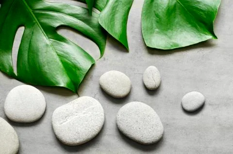 Flat lay composition with spa stones, palm leaves on grey background. Stock Photos