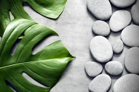 Flat lay composition with spa stones, palm leaves on grey background. Stock Photos