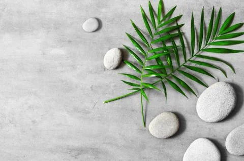 Flat lay composition with spa stones, palm leaves on grey background. Stock Photos