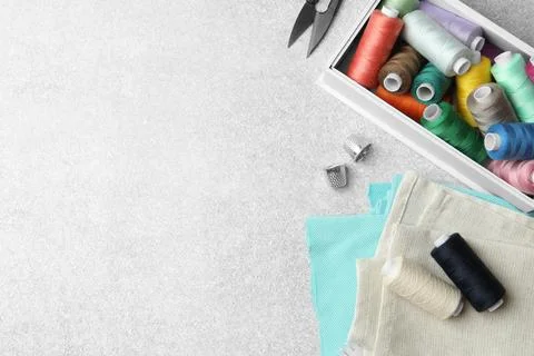 Flat lay composition with spools of threads and sewing tools on light backg.. Stock Photos
