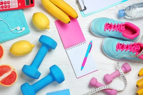 Flat lay composition with sport items, healthy food and notebook on wooden ba Stock Photos