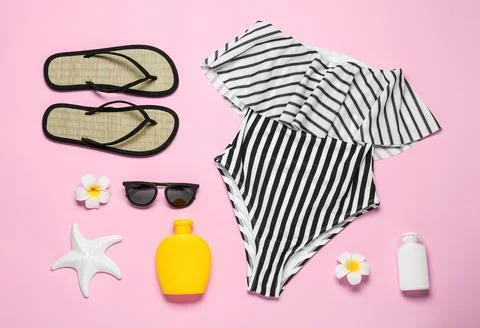 Flat lay composition with striped swimsuit and beach accessories on pink back Foto stock