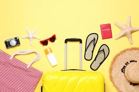 Flat lay composition with suitcase and beach objects on yellow background Stock Photos