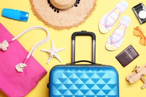 Flat lay composition with suitcase and beach objects on yellow background Stock Photos