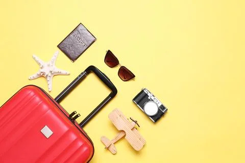 Flat lay composition with suitcase and beach objects on yellow background. Sp Fotos de archivo