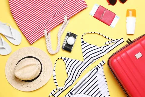 Flat lay composition with suitcase and beach objects on yellow background Fotos de archivo