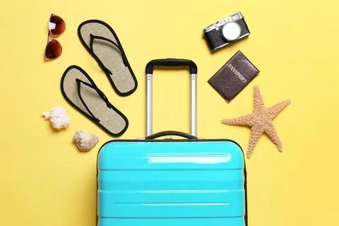 Flat lay composition with suitcase and beach objects on yellow background 스톡 사진