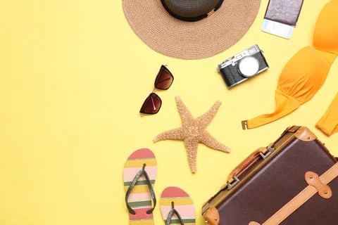 Flat lay composition with suitcase and beach objects on yellow background Stock Photos