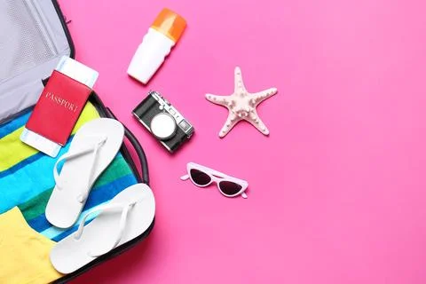 Flat lay composition with suitcase and beach objects on pink background Stock Photos