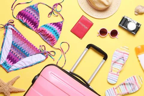 Flat lay composition with suitcase and beach objects on yellow background Fotos de archivo