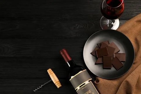 Flat lay composition with tasty red wine and chocolate on black wooden table. Foto stock