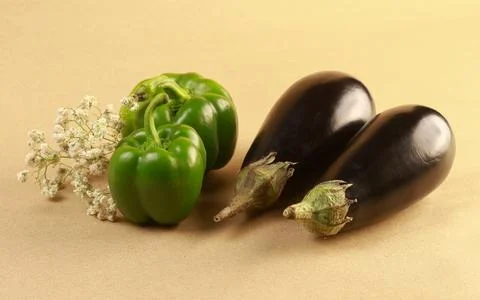 Flat-lay composition of two eggplants with two green peppers and decorative Stock Photos